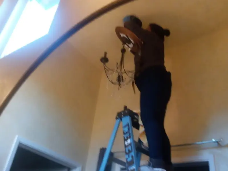 Electrician installing a chandelier in a Essex residence